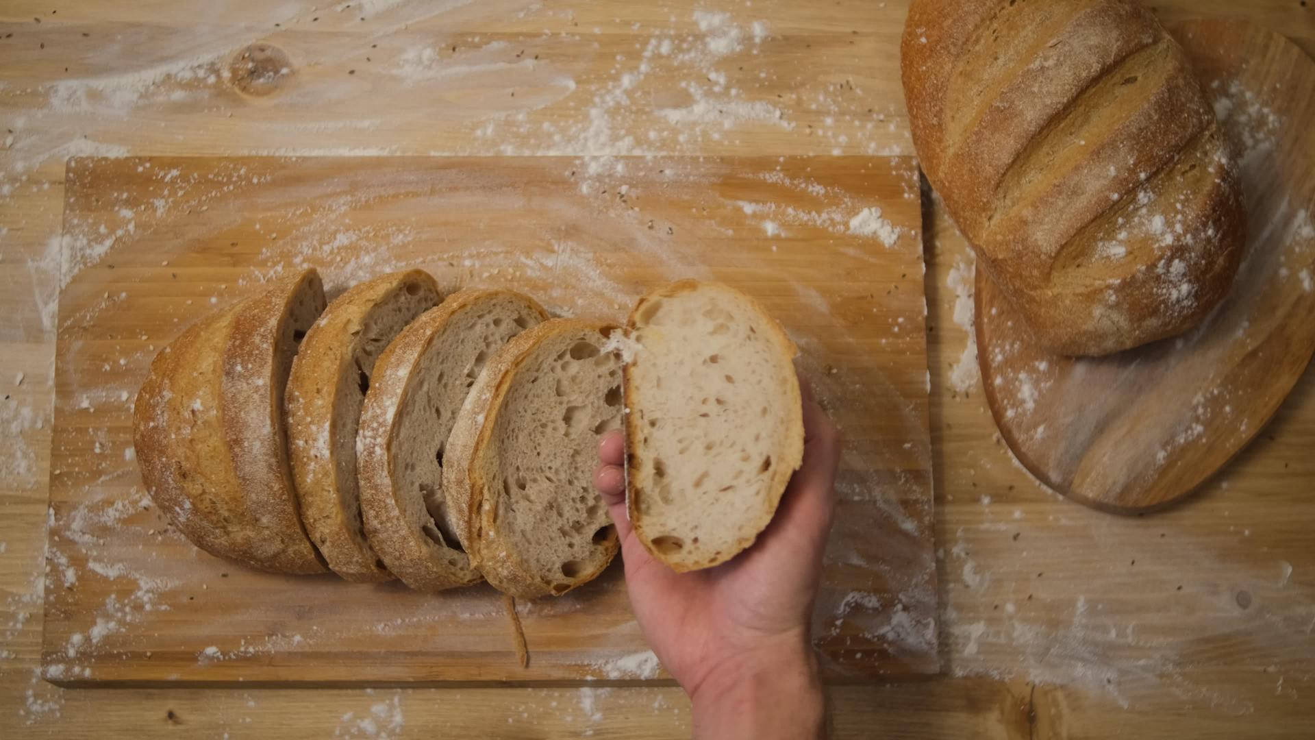 一个男人看着厨房里的一块面包把面包切成三明治视频的预览图