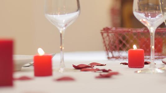 服务员打扮成情人节浪漫晚餐或婚礼红蜡烛玫瑰花瓣酒杯视频的预览图