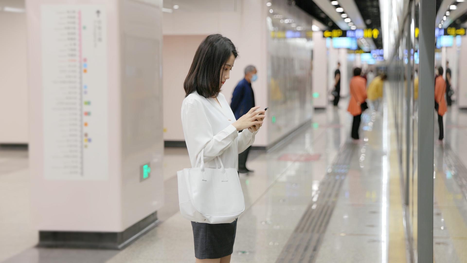 女生等地铁的间隙玩手机视频的预览图