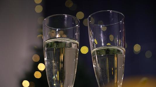 在圣诞节或新年园艺的背景下两杯香槟点亮了红酒节日的灯光视频的预览图