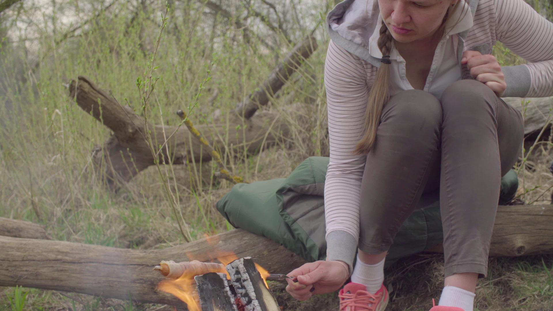 年轻女子在火上烤香肠视频的预览图