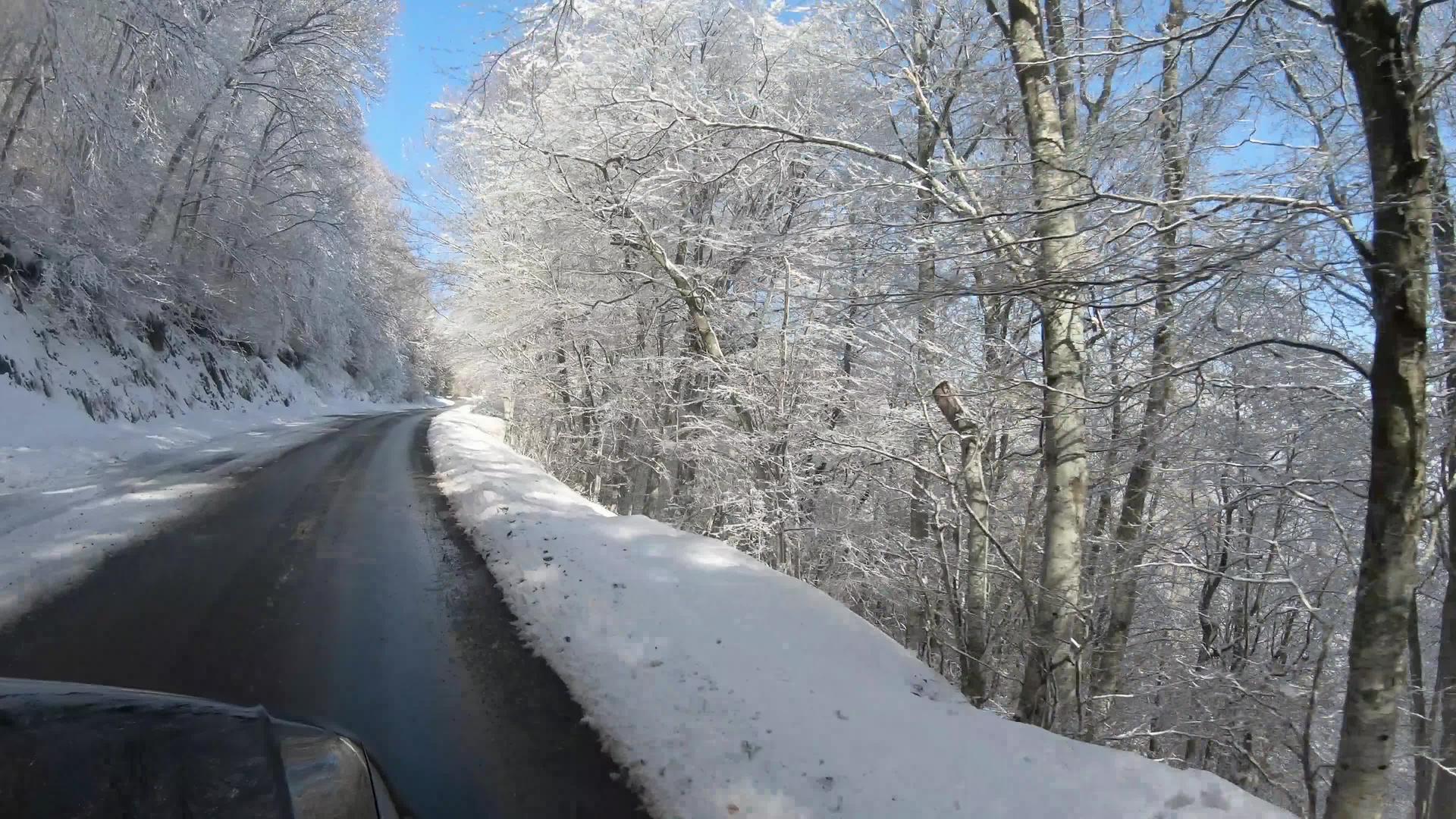 在空旷的道路上驾驶着被雪覆盖的地貌美丽的冬季背景视频的预览图