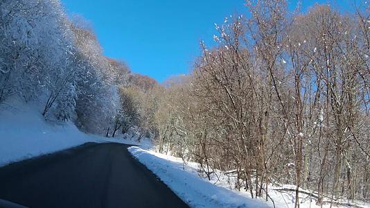 在山路上行驶冬天的森林风景和被雪覆盖的荒野视频的预览图