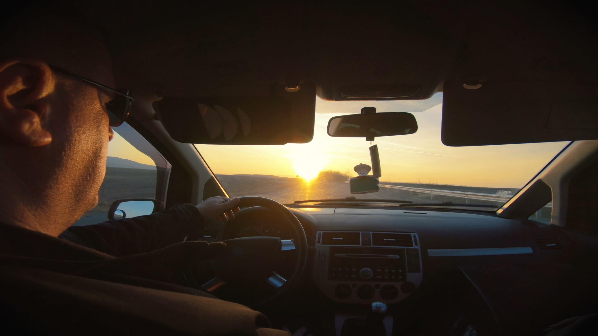 男子沿着高速公路驾驶汽车阳光照耀着挡风玻璃视频的预览图