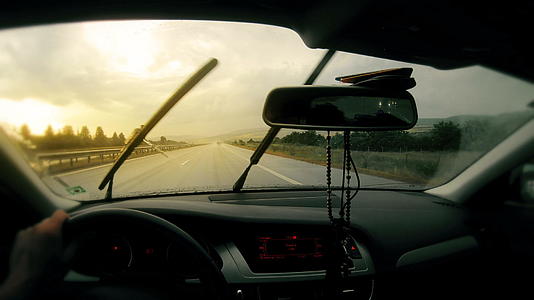 暴风雨中挡风玻璃上的雨在恶劣天气下驾车向日落行驶视频的预览图