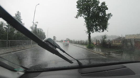 汽车在大雨中轻轻地在窗户上开着水滴视频的预览图