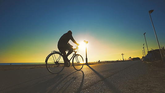 夏天在日出天空的沙滩沥青走道上骑旧自行车视频的预览图