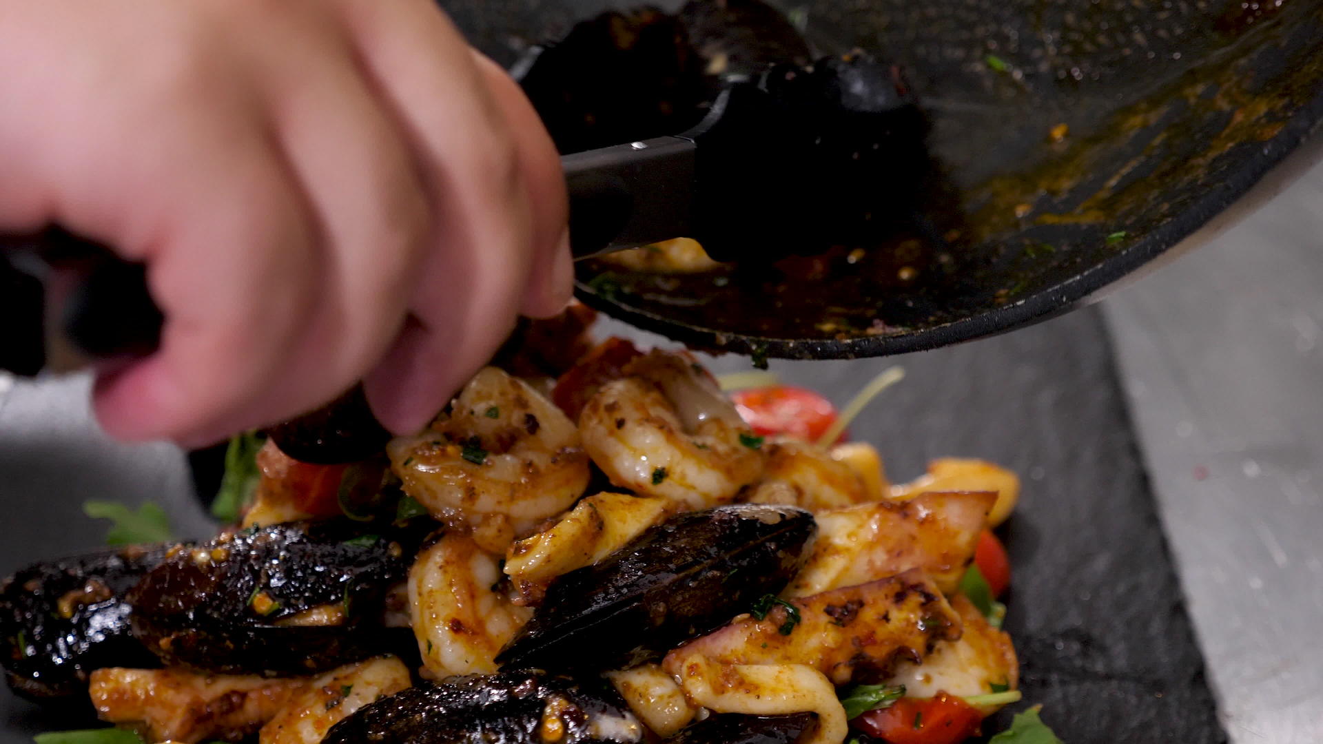厨师和手里拿着钳子的厨师把煮熟的海鲜放在手里视频的预览图