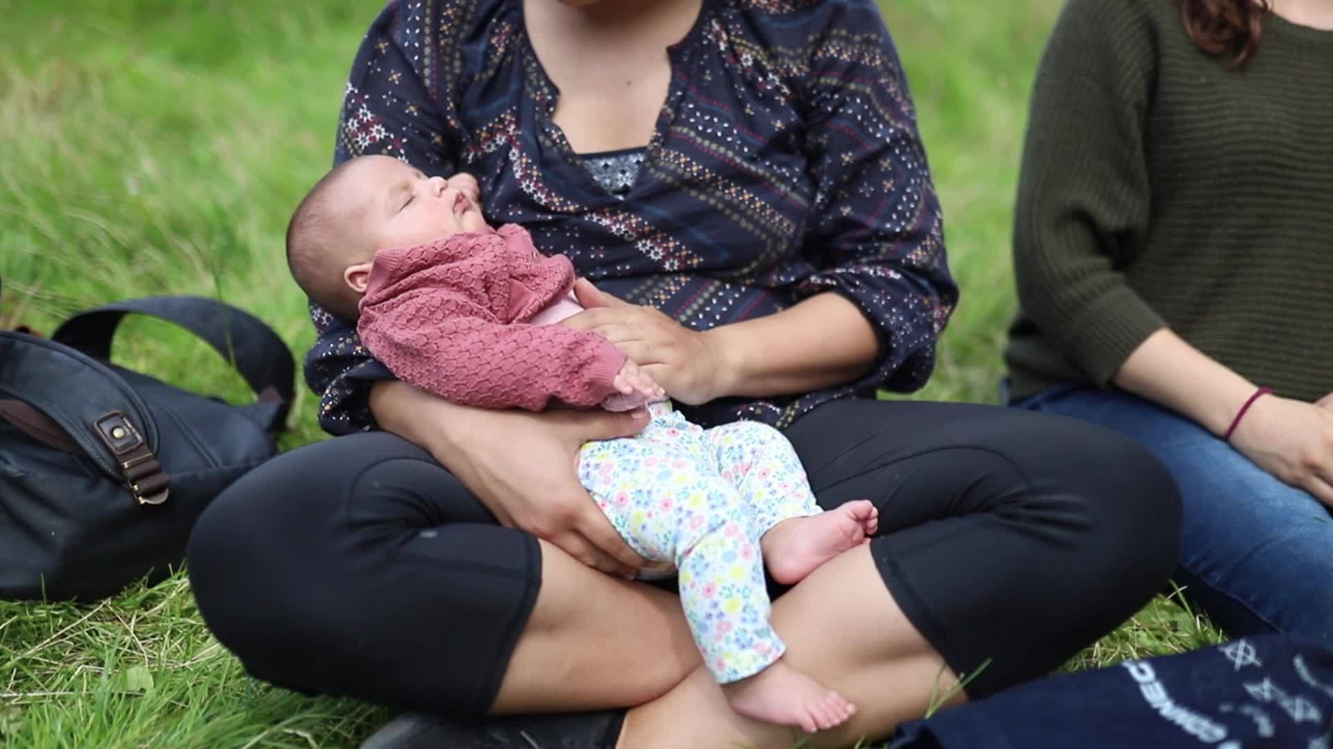 当母亲坐在草地上时她把女婴抱在怀里视频的预览图