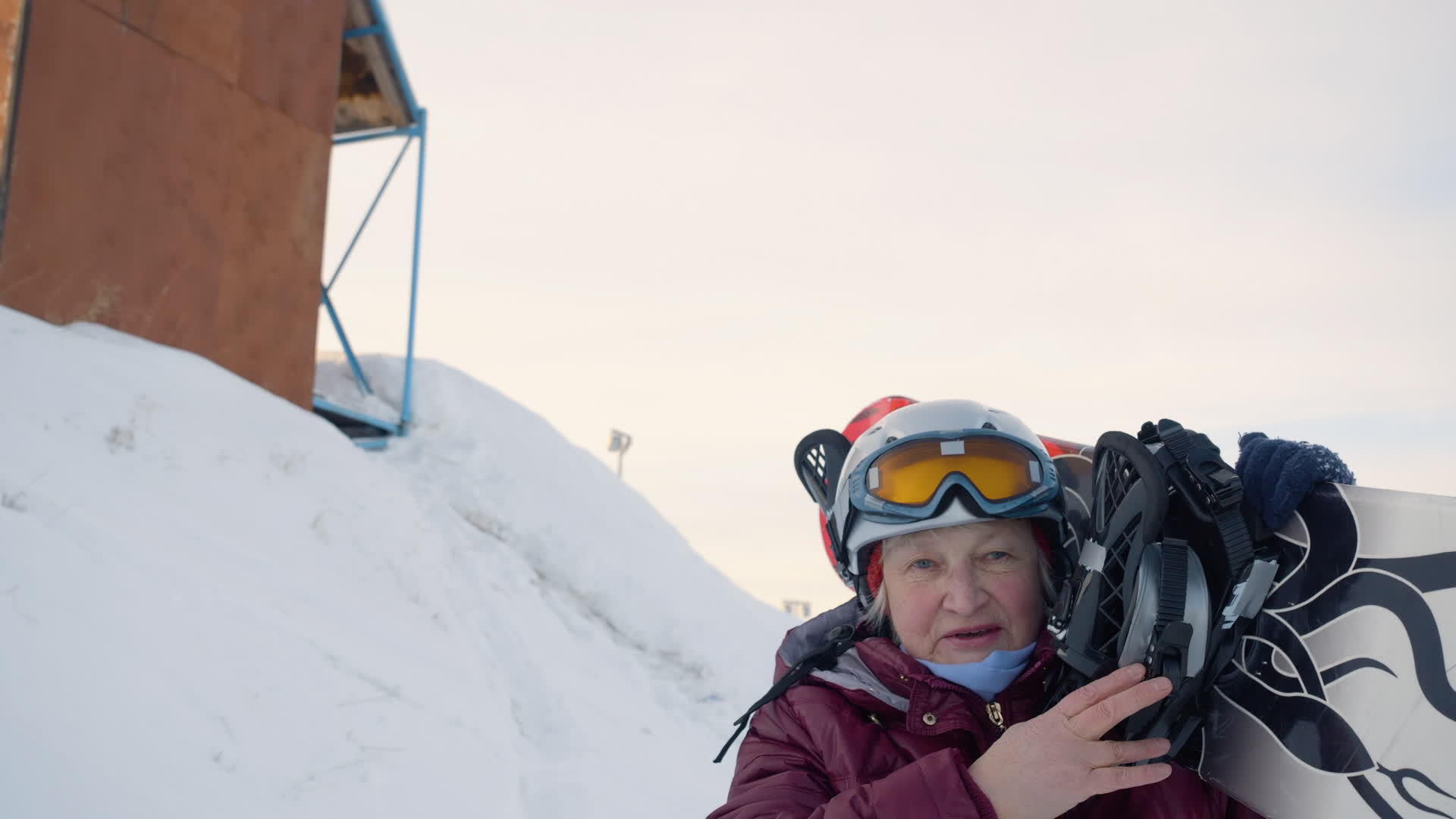 在冬季度假胜地的雪坡上高级女性走在肩膀上靠着雪板打雪板视频的预览图