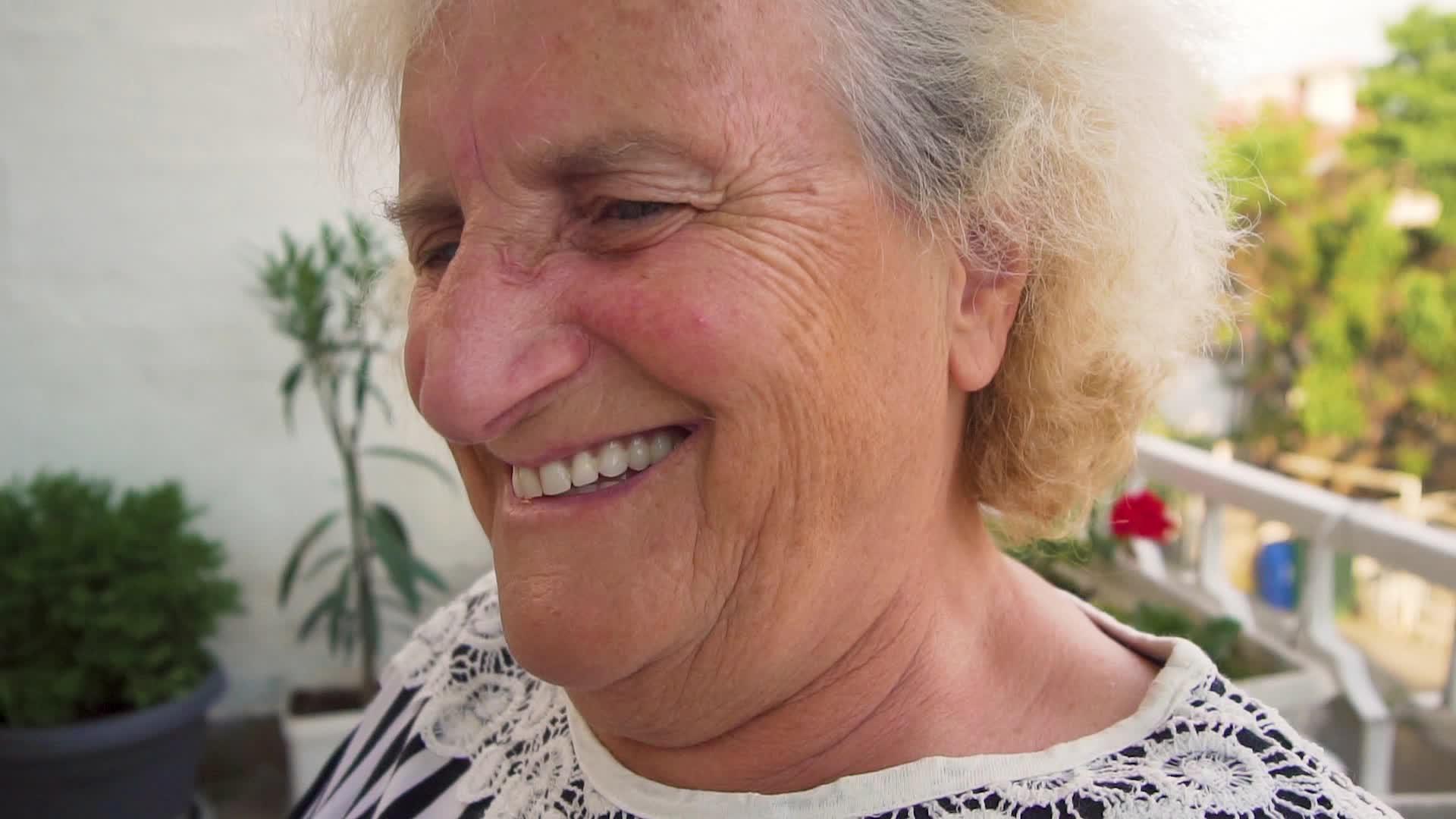 年长女士的快乐肖像坐在外面日落时微笑慢慢移动视频的预览图