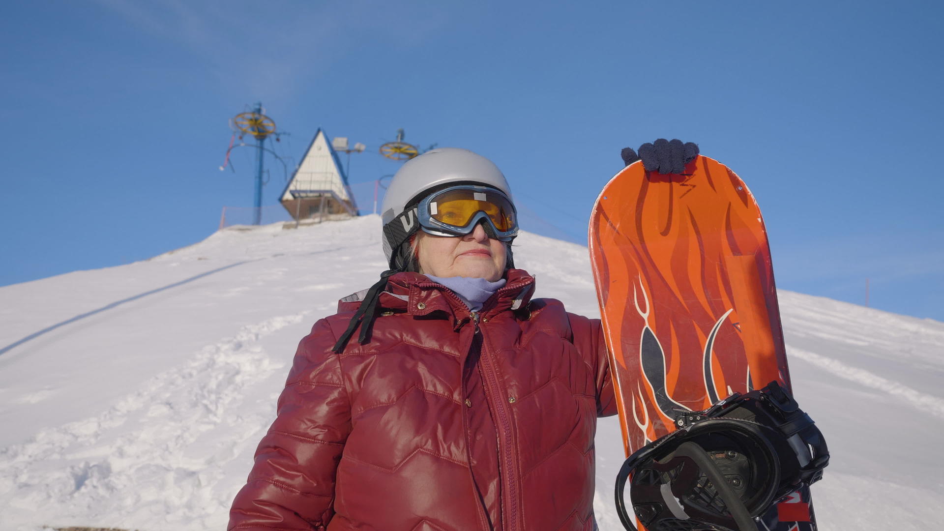 雪山上穿着红色外套的高级女子拿着滑板视频的预览图