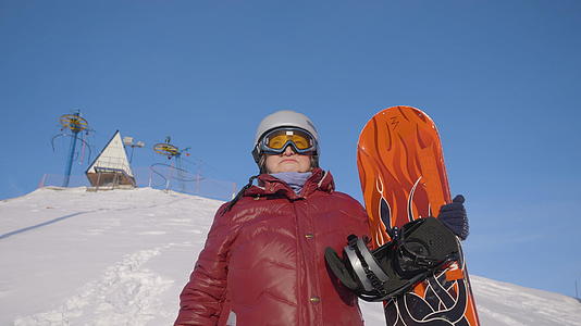 山上冬季度假胜地雪坡上站着雪板的高级女性视频的预览图