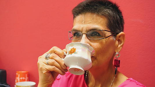 一个在白杯里喝茶的美丽的老妇人视频的预览图