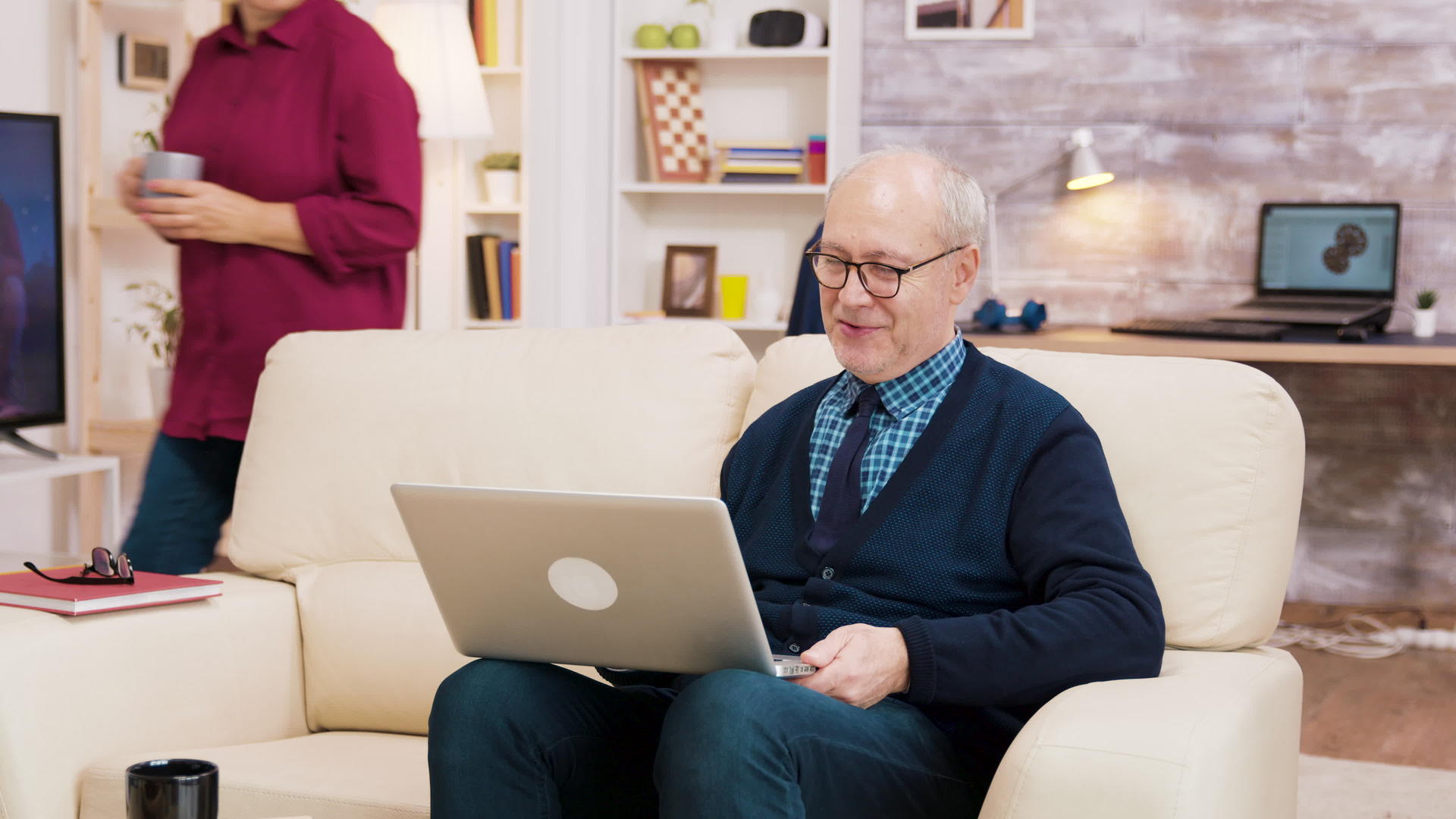 这对老夫妇在笔记本电脑视频通话中戴着眼镜坐在沙发上视频的预览图