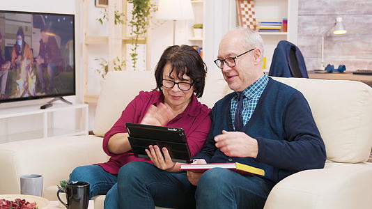 一对坐在沙发上的老夫妇在平板电脑上打视频电话视频的预览图