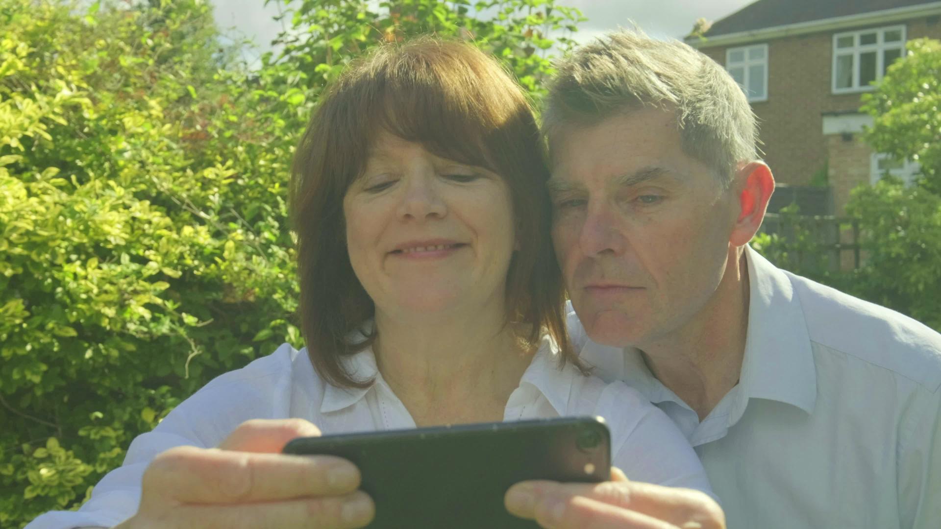 现代老年夫妇在智能手机上自拍和制作有趣的面孔视频的预览图