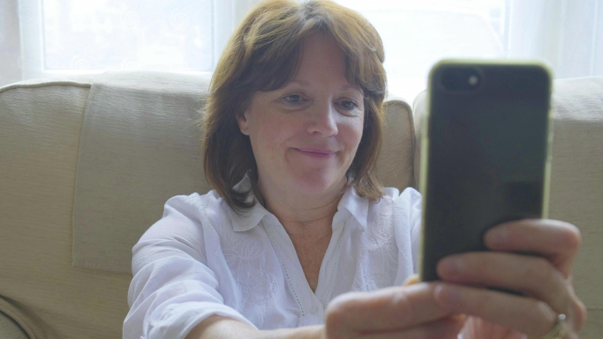 现代老年女性在智能手机上自拍视频的预览图