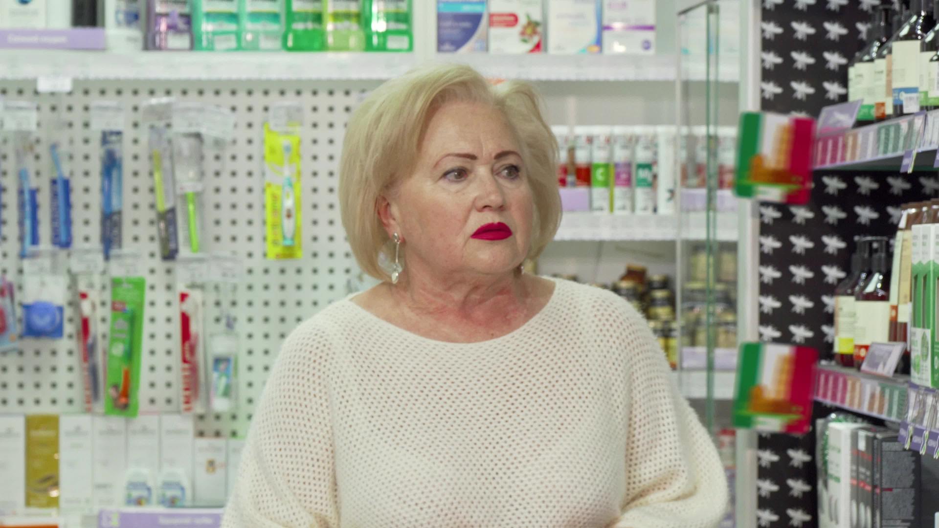 在药店货架上寻找药品的高级女高级官员视频的预览图