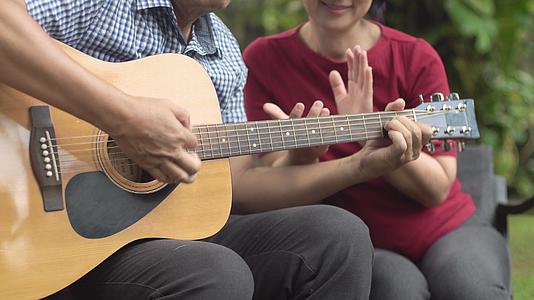 中年夫妇坐在后院的长椅上弹吉他时放松视频的预览图