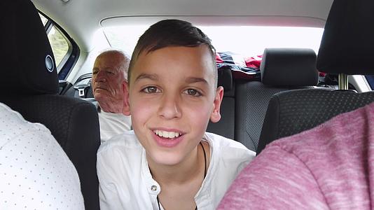 男孩和他的祖父坐在汽车的后座上视频的预览图