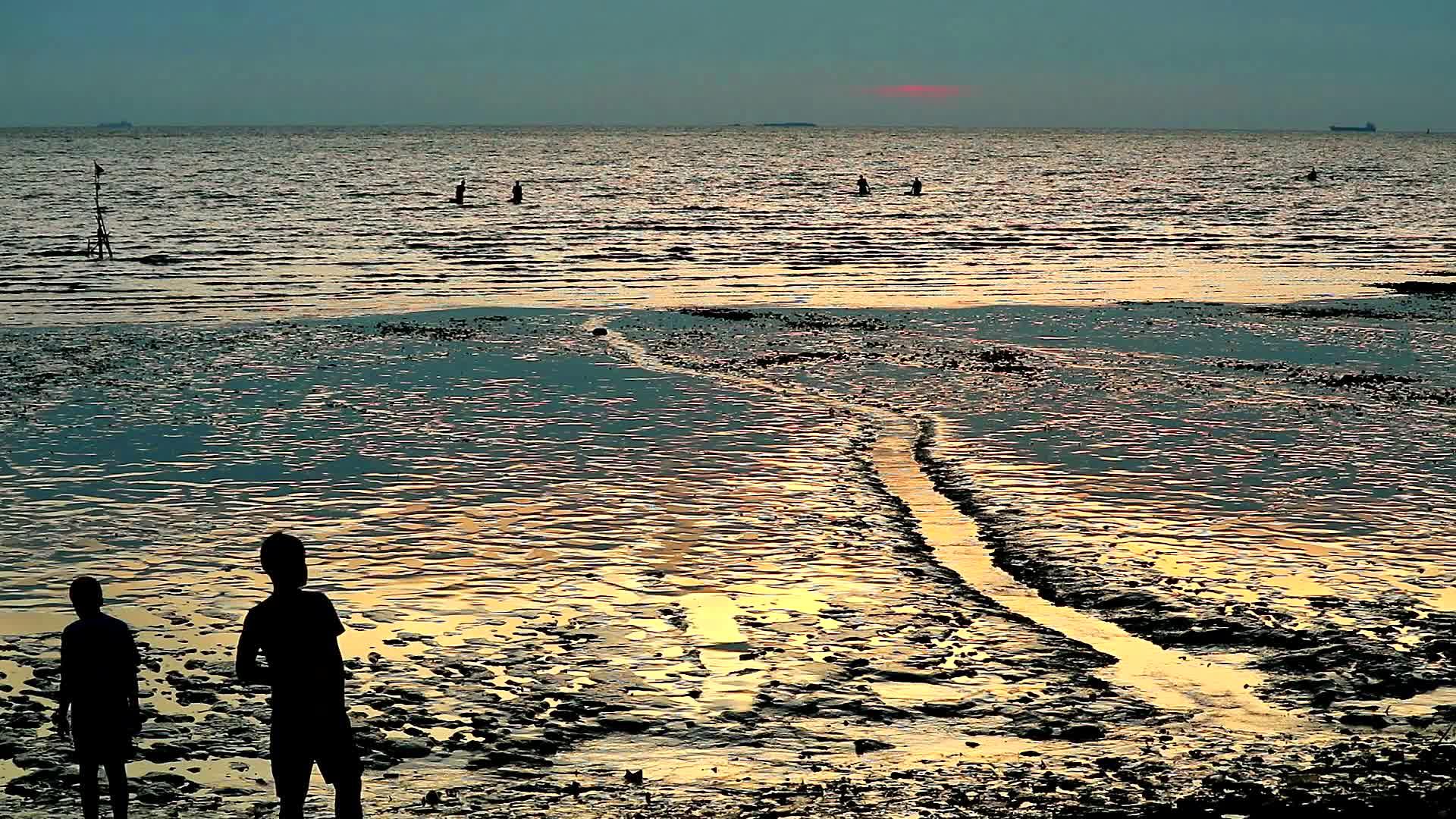 当日落和大潮时休眠男子在海滩上行走视频的预览图