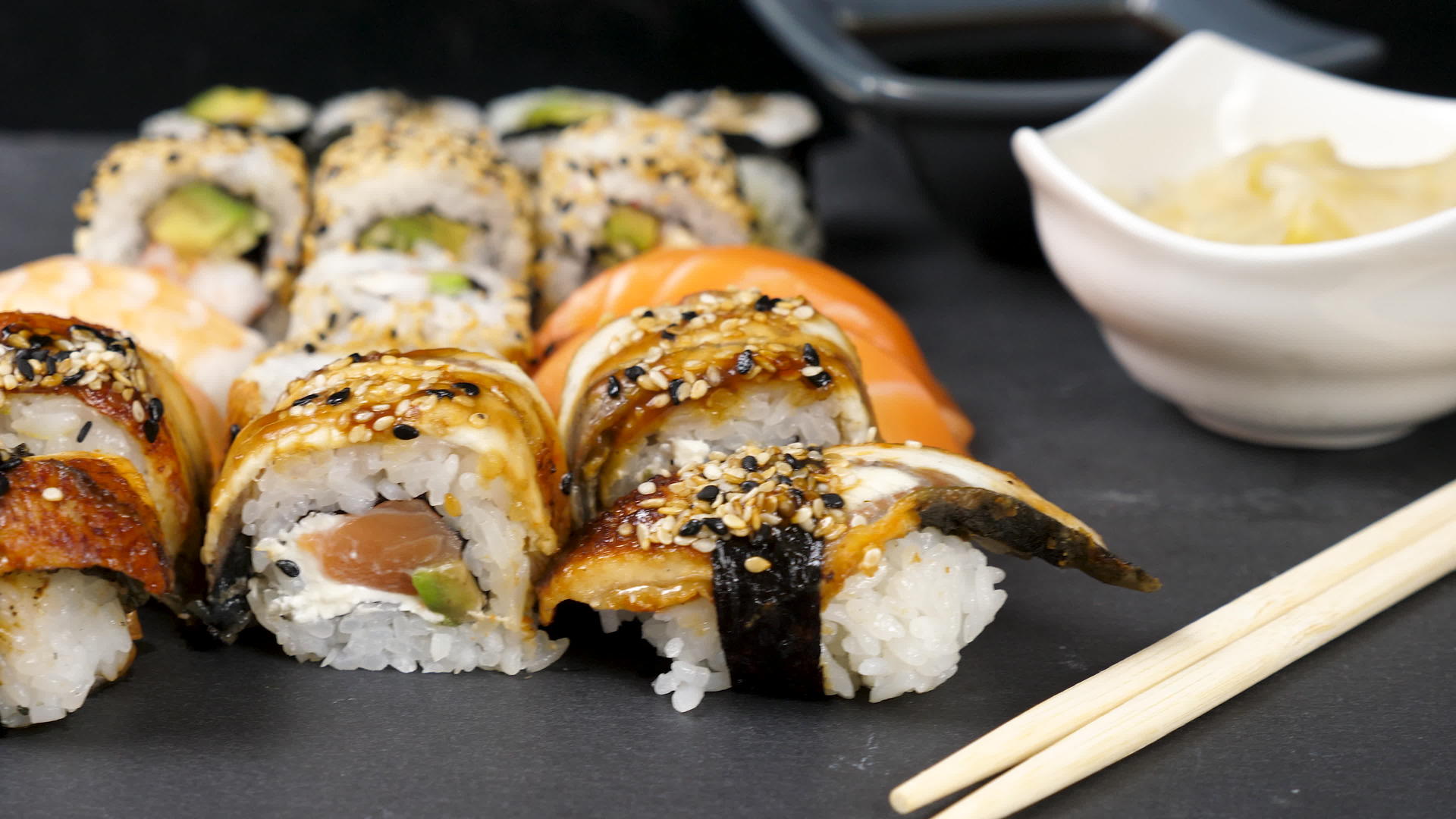 各种不同的寿司卷组合在黑黑石背景上视频的预览图