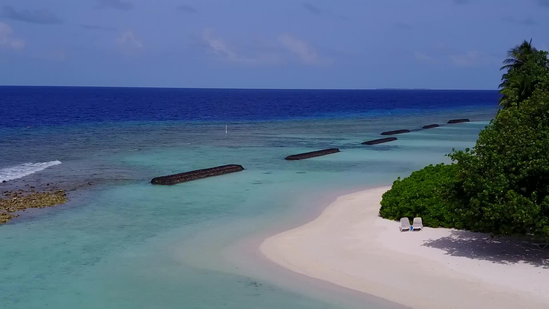 环礁湖周围的豪华海滩在蓝色的绿色海洋和清洁的沙地背景下航行视频的预览图
