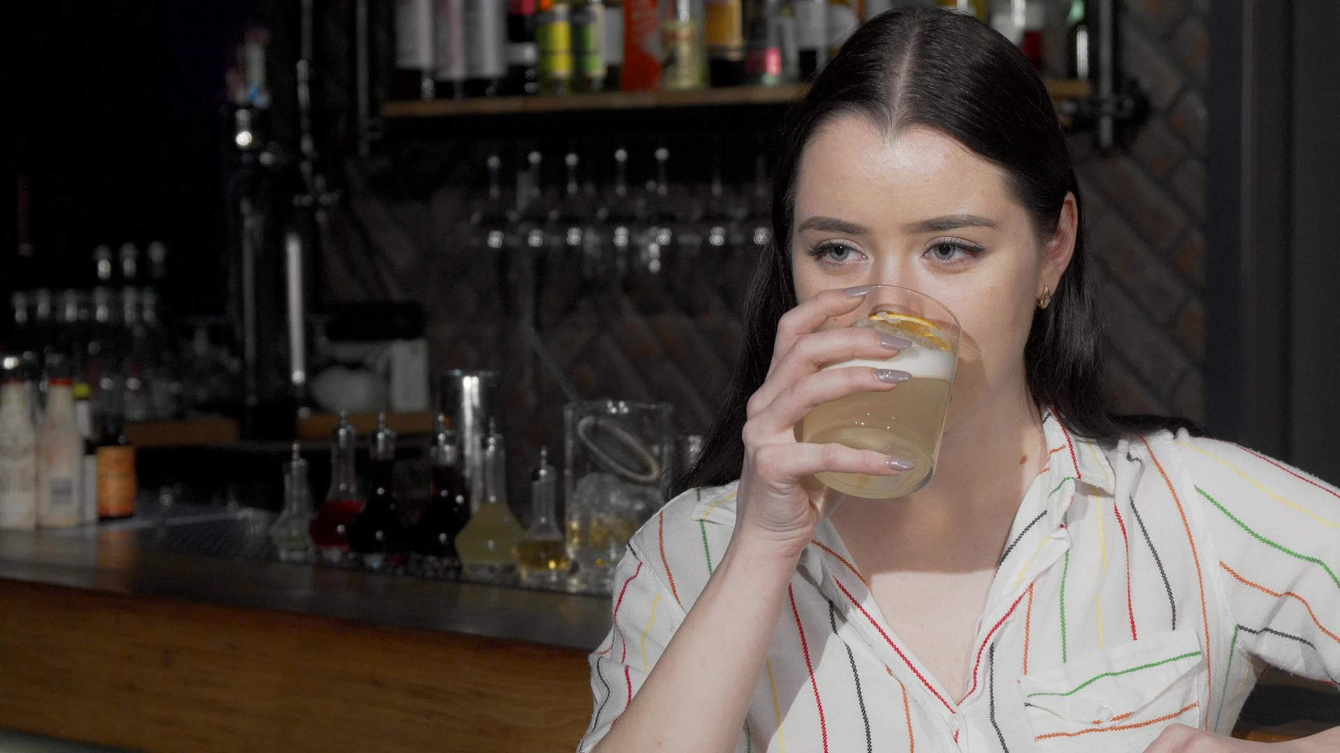一个迷人的年轻女子在酒吧喝鸡尾酒时对着相机微笑视频的预览图