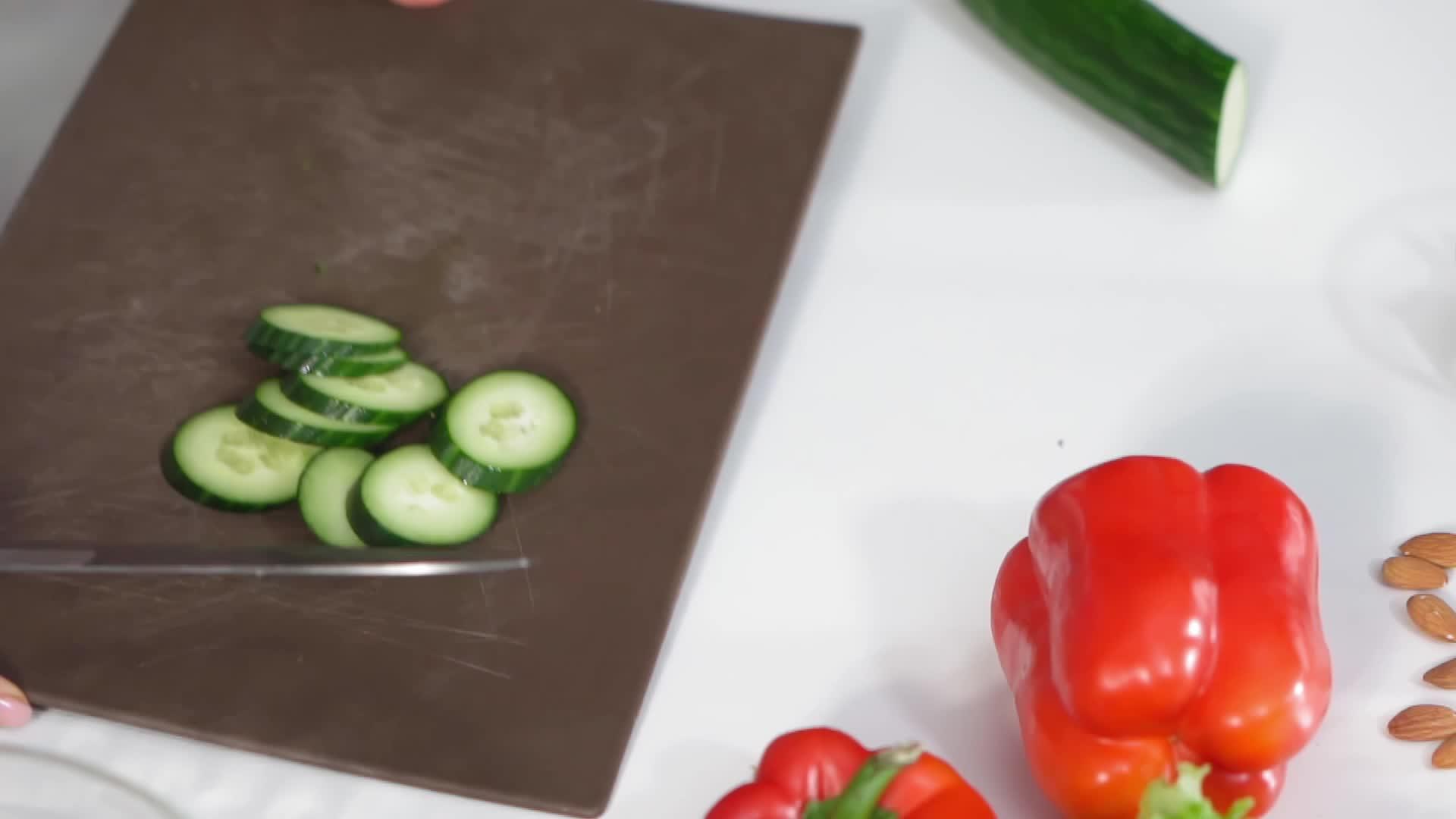菜板上的新鲜黄瓜片被扔进一个普通的沙拉碗里站在厨房里视频的预览图