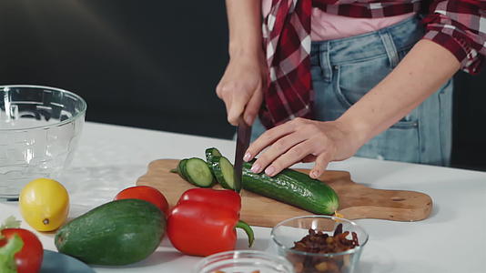 在桌子上切下新鲜的黄瓜片轻轻地站在厨房里吃午饭或晚餐视频的预览图