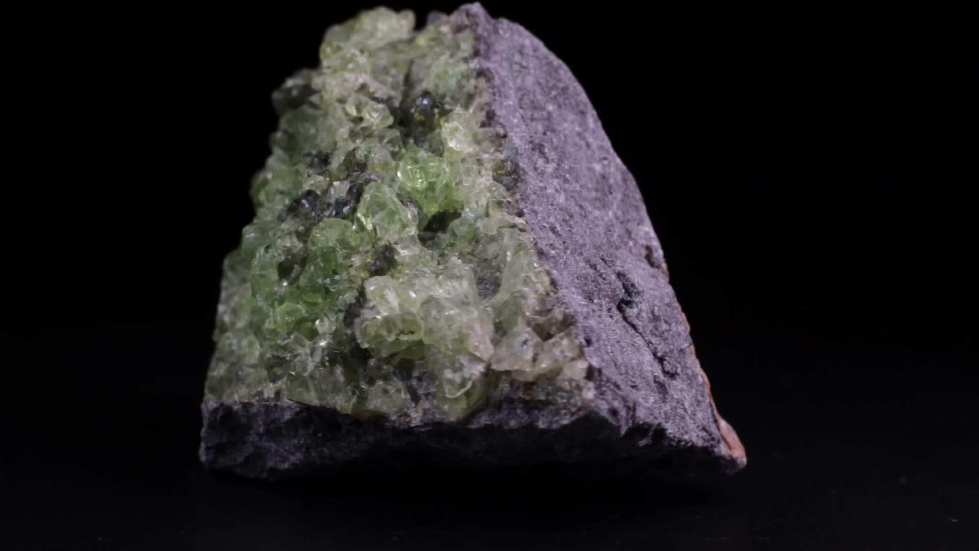 橄榄石或橄榄石晶体在黑色背景上缓慢旋转视频的预览图