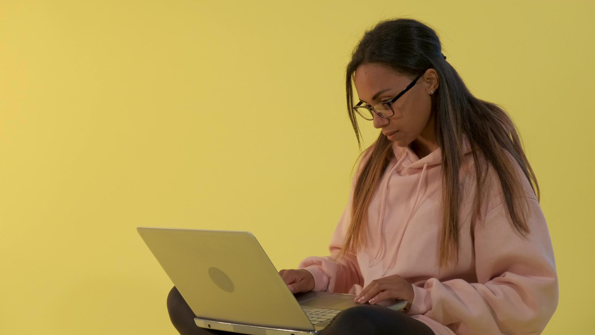 从事黄色背景计算机工作的年轻女性混合种族混血种族视频的预览图