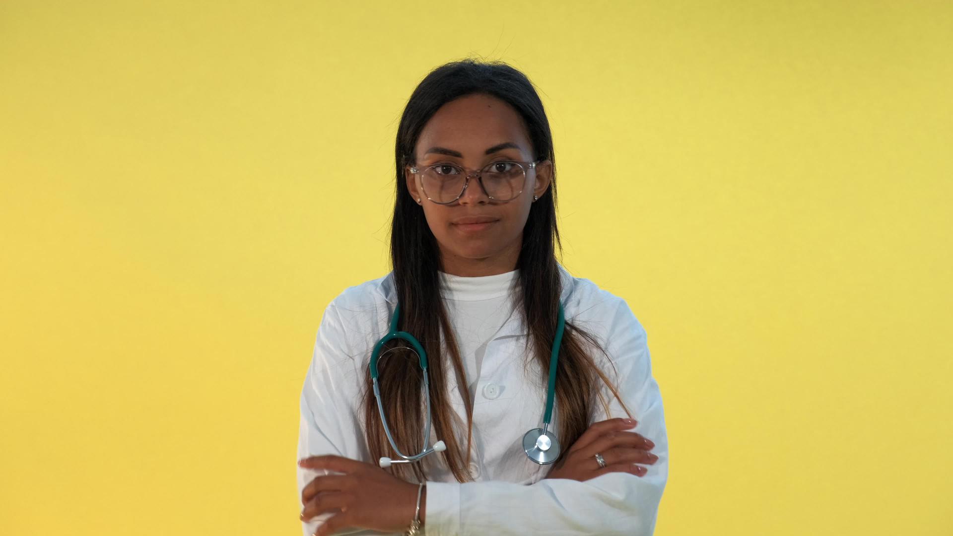 关闭混合种族的女医生用黄色背景伸出两边的缝隙视频的预览图
