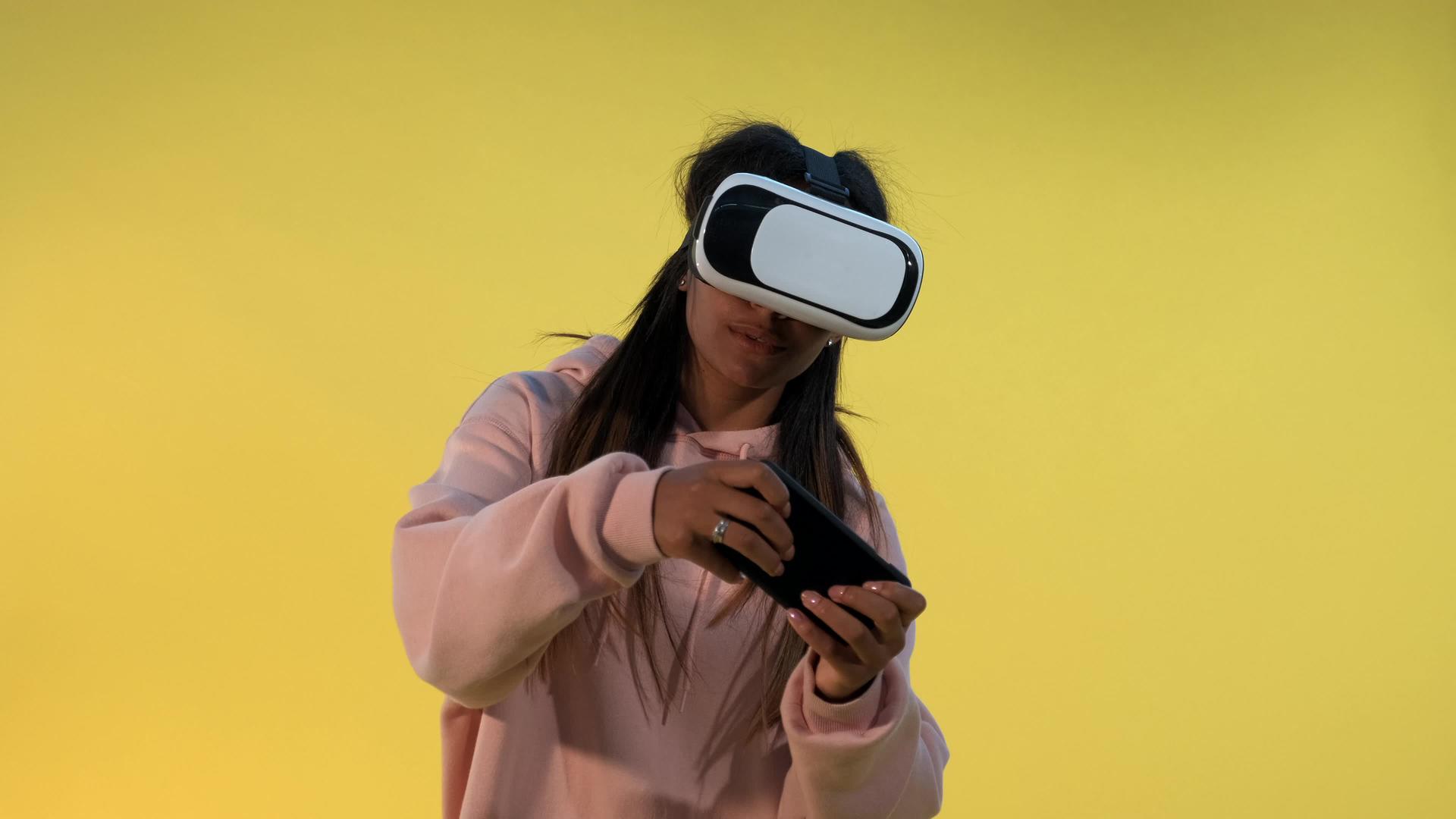 虚拟现实眼镜中的多种族女孩用智能手机玩网络游戏视频的预览图