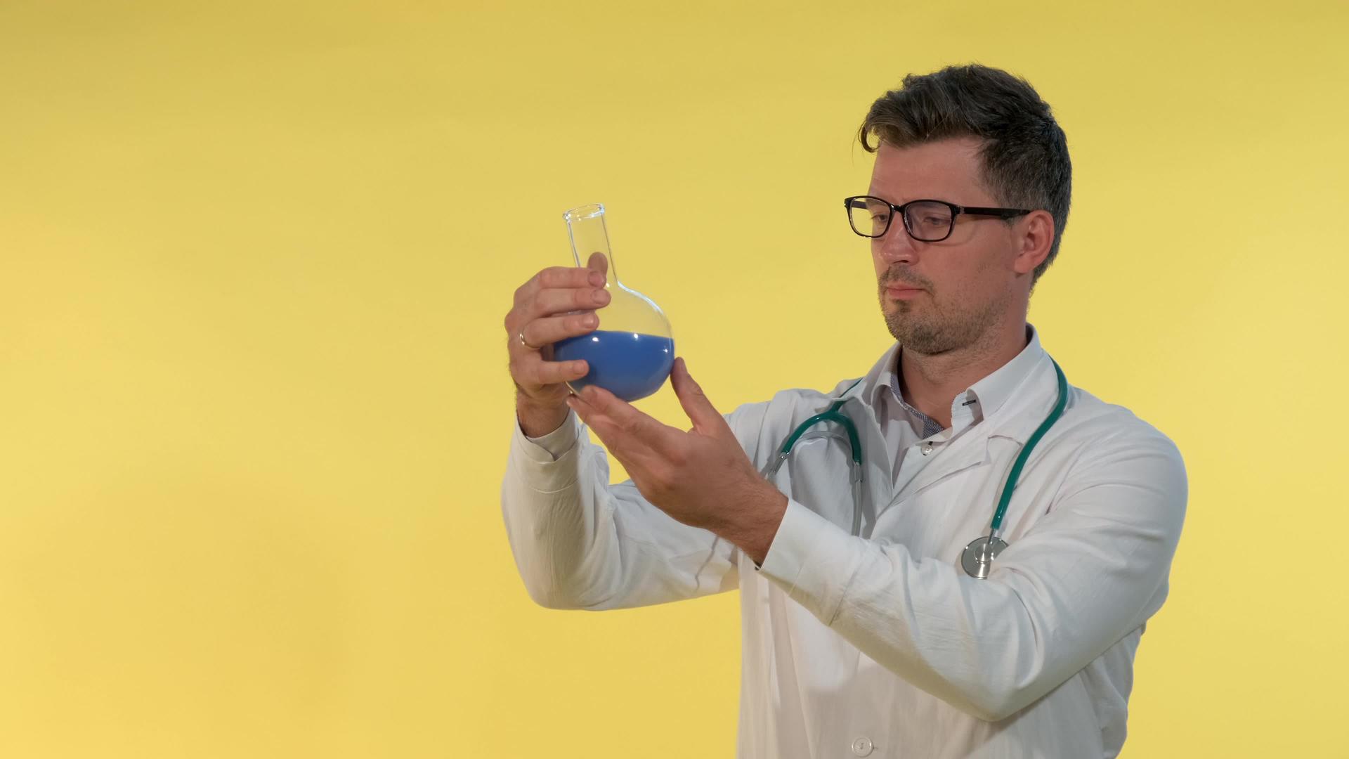 穿着实验室外套和眼镜的年轻医生正在用蓝色液体进行检查视频的预览图
