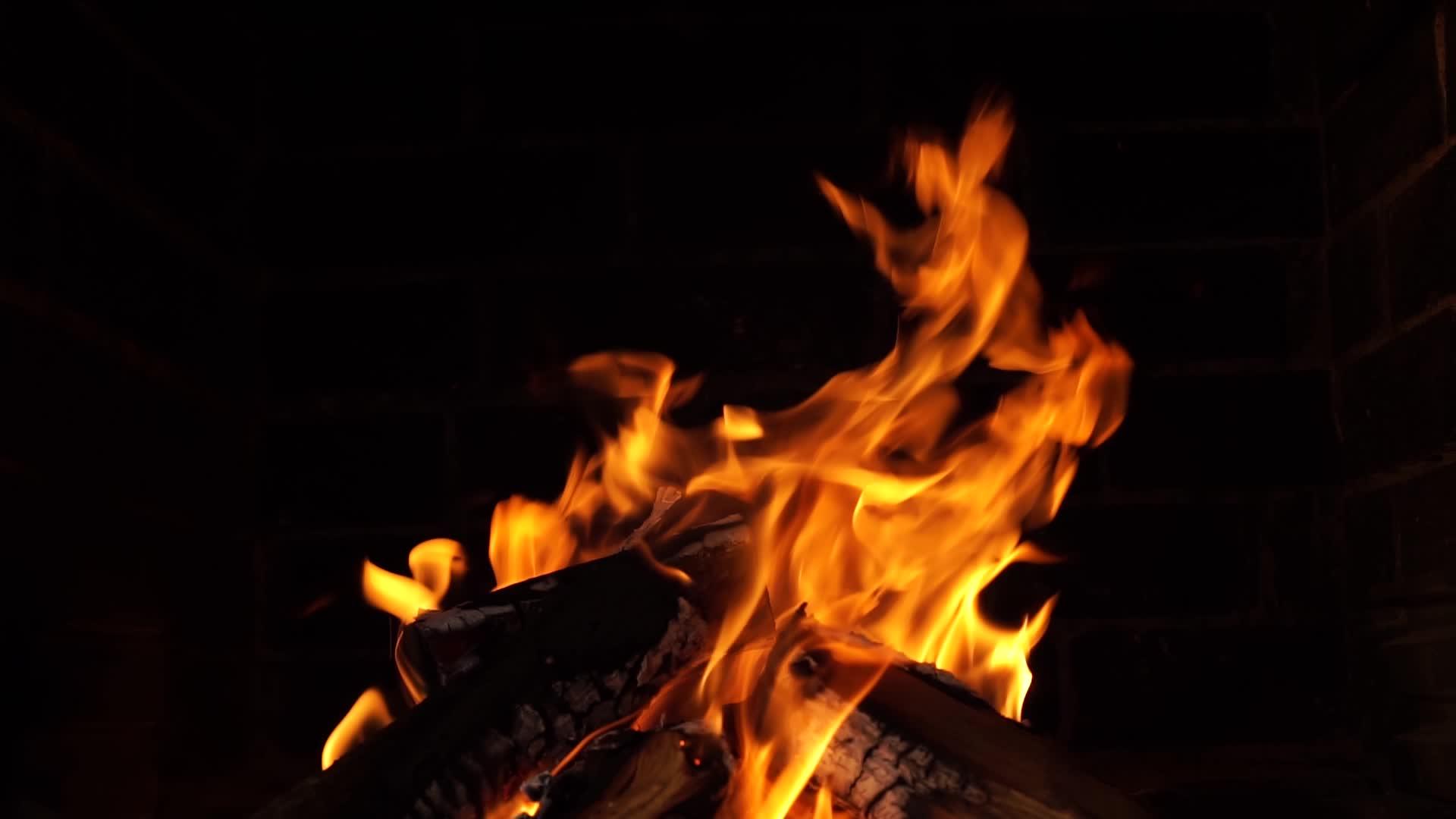 在火焰中燃烧的橡木柴火和在黑色背景下燃烧的余烬视频的预览图