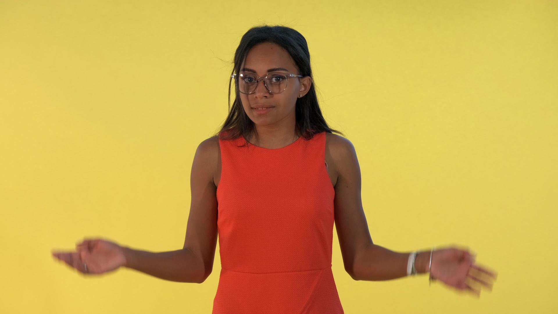 年轻女子将双手伸向两侧并说出黄色背景的真面目视频的预览图