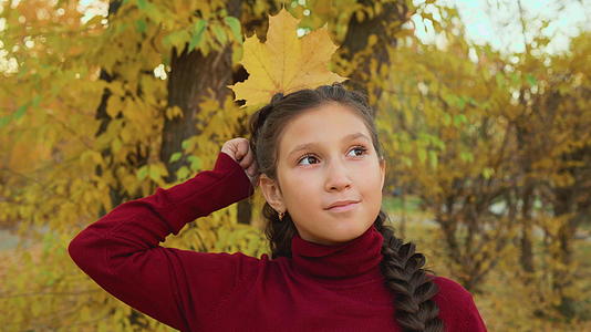 在秋天的公园里黑发女孩像女王一样在头后拿着枫叶辫子视频的预览图