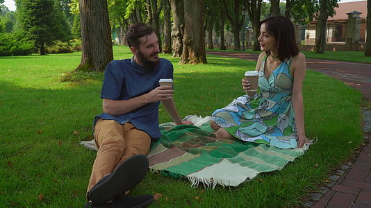 情侣们坐在公园的草坪上聊天喝咖啡视频的预览图