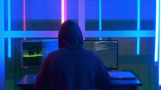 在黑色夹克和头上戴口袋帽的黑客写黑客程序视频的预览图