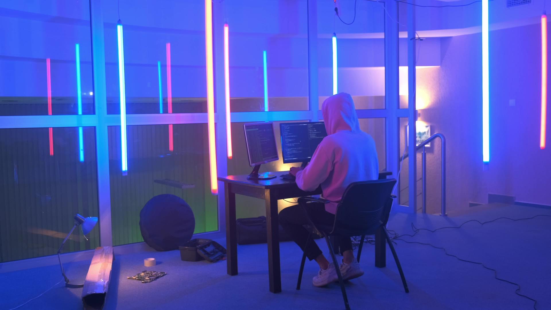 黑客在一个有彩色荧光灯的房间里工作视频的预览图