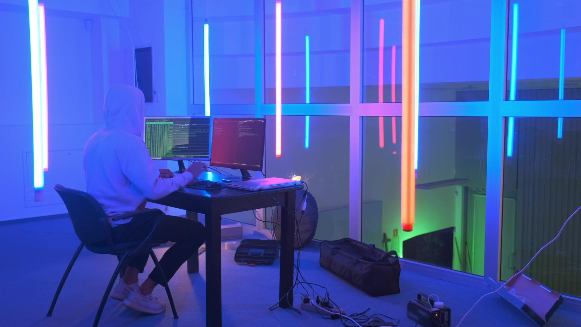 黑客在一个有彩色荧光灯的房间里工作视频的预览图