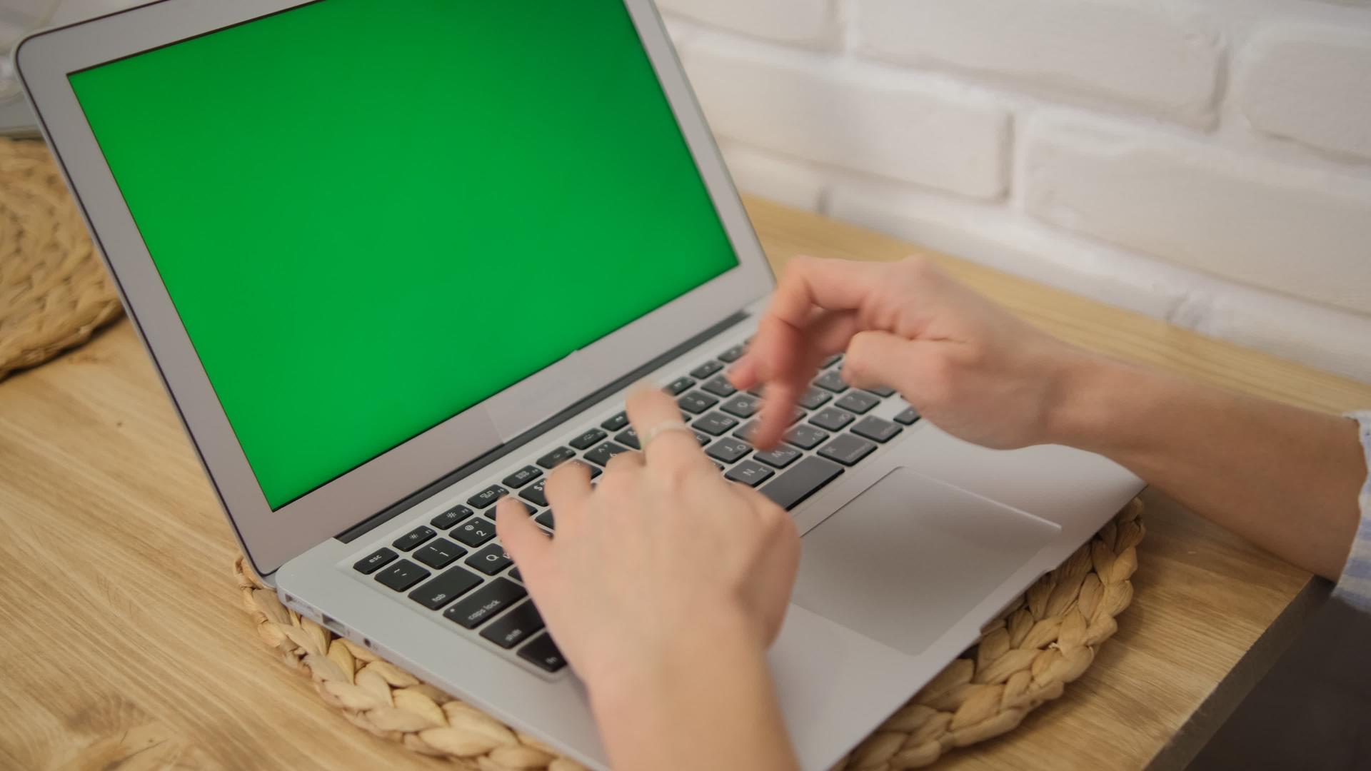 带有绿色屏幕的笔记本电脑在键盘上工作的手的特写镜头远程工作视频的预览图