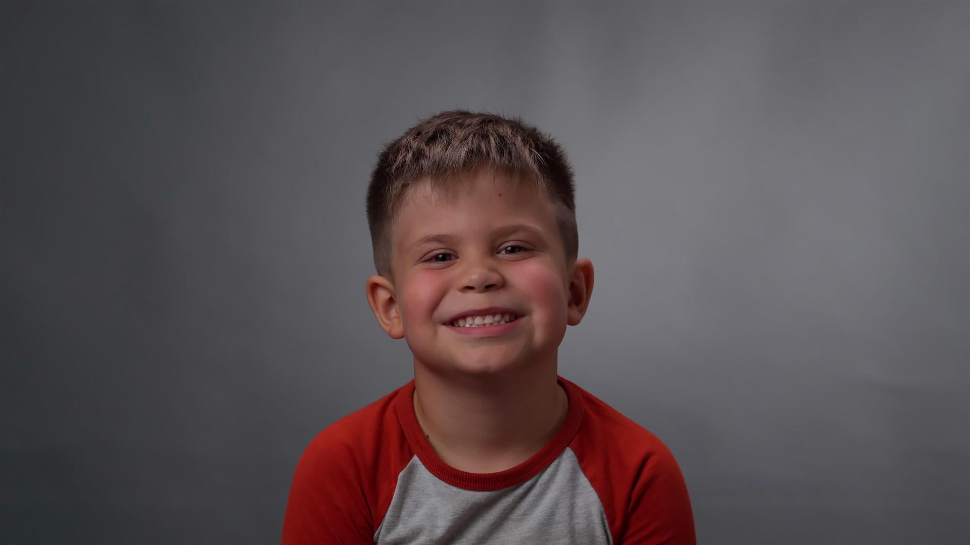 一个小男孩的脸在深灰色或黑色的背景下被孤立在相机上视频的预览图