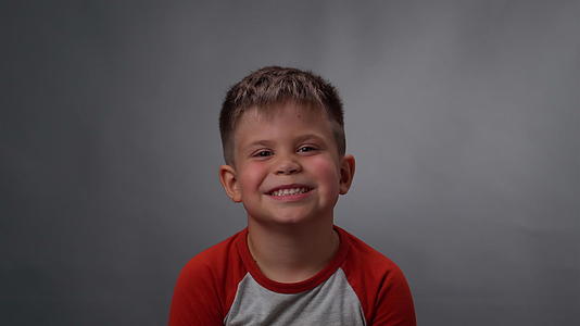 一个小男孩的脸在深灰色或黑色的背景下被孤立在相机上视频的预览图
