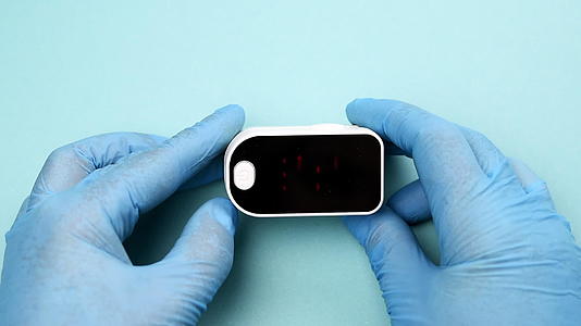 一位戴着蓝色乳胶手套的医生拿着电子脉冲血氧表视频的预览图