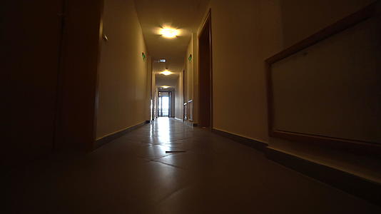 低角度穿过长长的深黑色建筑走廊拍摄电影领域的平面镜头视频的预览图