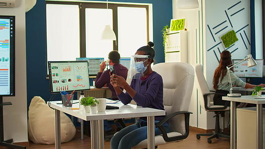 黑人女性在新的普通办公室使用智能手机浏览视频的预览图
