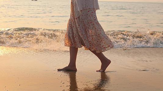 赤脚女孩在温暖的阳光下沿着潮湿的沙滩视频的预览图